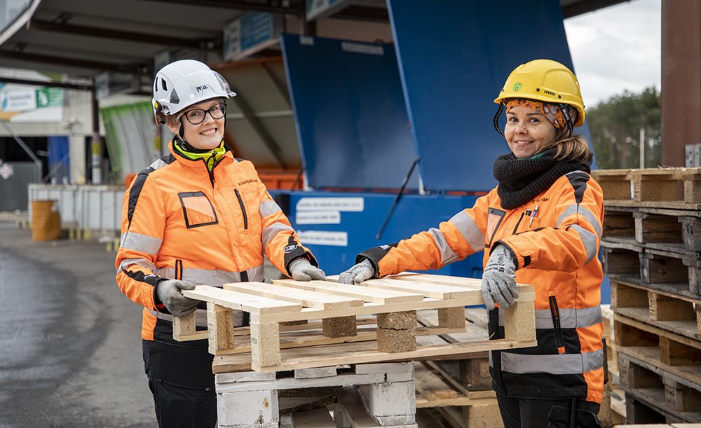 kaksi hymyilevää työntekijää pitelee kiinni kuormalavasta Ruskon jätekeskuksen oivapisteellä
