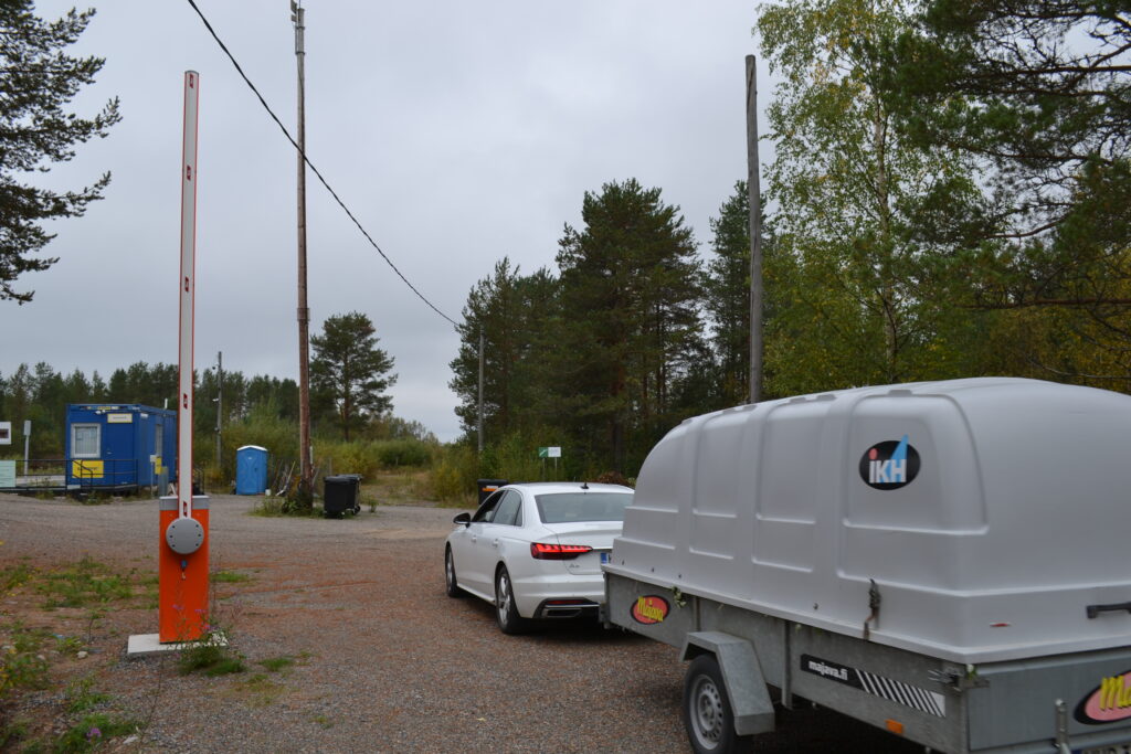 Peräkärryä vetävä henkilöauto ajaa avoinna olevasta puomiportista läpi.