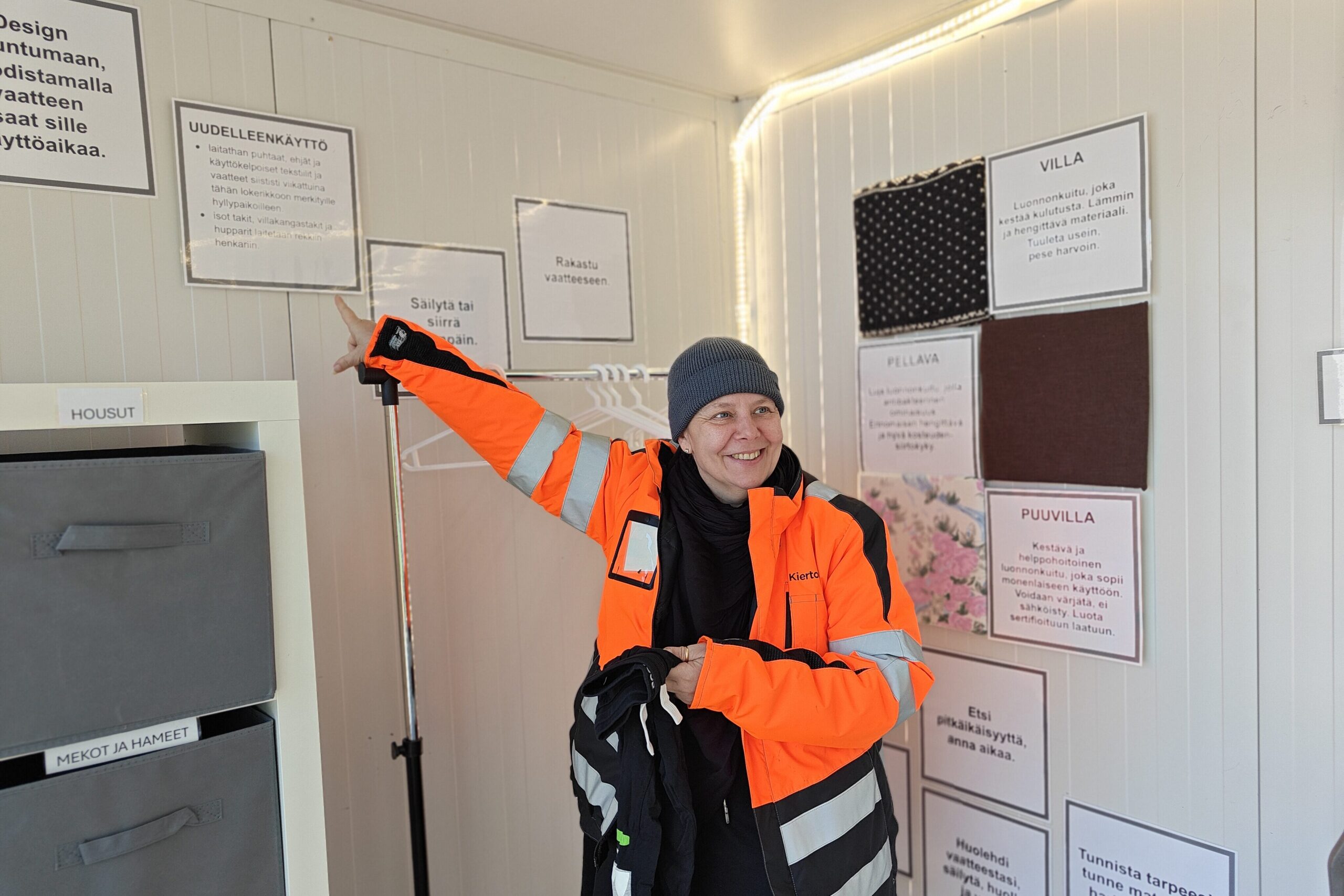 Mari Juntunen osoittaa kontin seinällä olevaa uudelleenkäytöst kertovaa tietoiskulappua hymyillen.