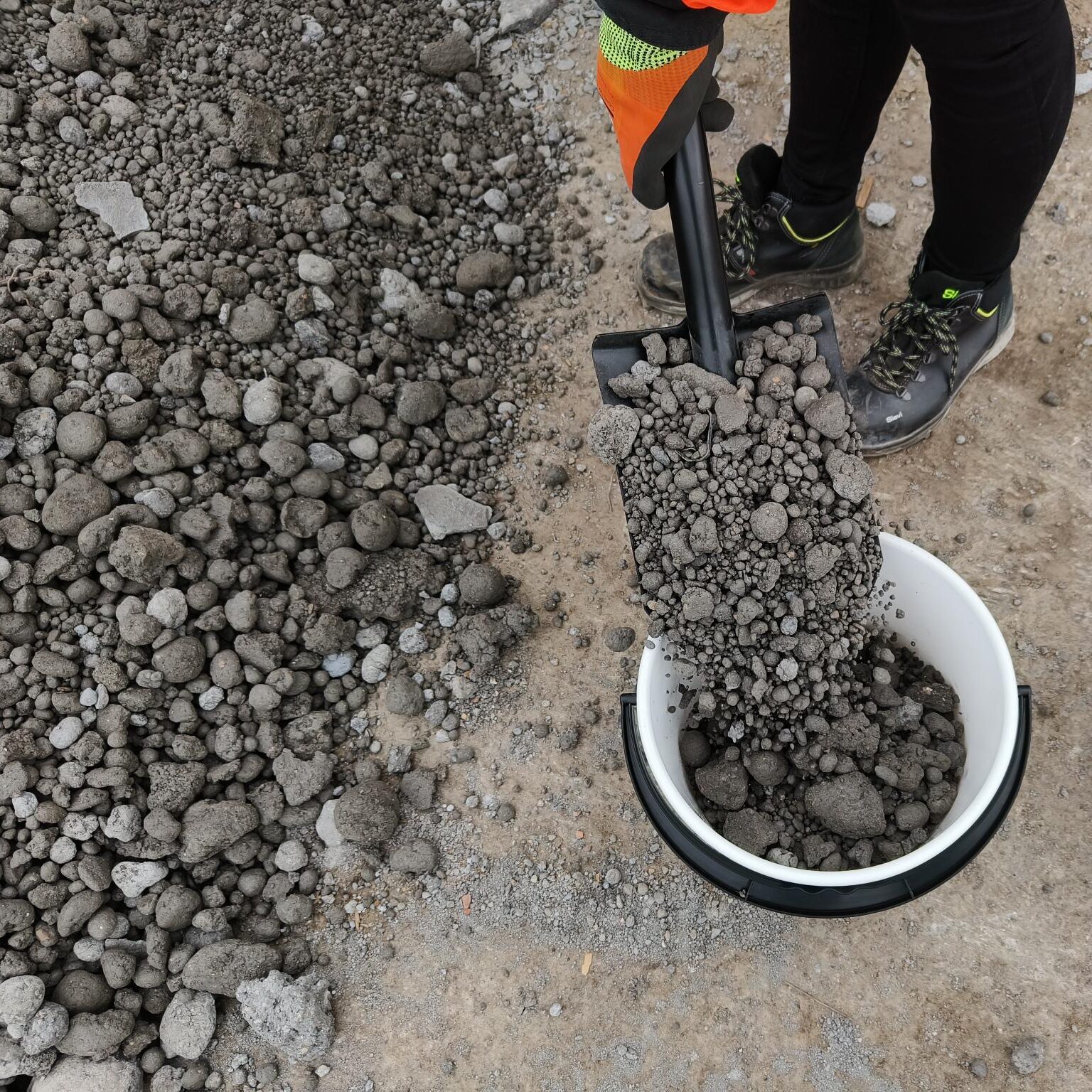 Tuhkasta valmistettuja maanrakennusrakeita lapiossa.
